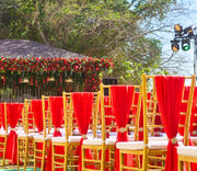 Decorative setup with red chairs and floral arrangements outdoors.