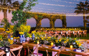 Evening outdoor event setup with tables, chairs, and decorative lights. 
