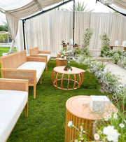 Outdoor patio with wicker furniture, tables, and white flowers on a grassy area.