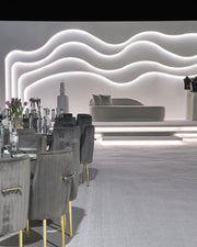 Modern interior design with gray chairs, a wavy light fixture, and a reception desk.