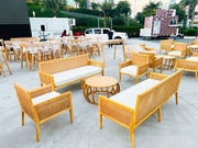 Outdoor furniture set with wooden chairs and benches on a concrete surface, with vehicles and greenery in the background.