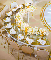 Elegant dining table set with floral arrangements and gold chairs in a formal setting.