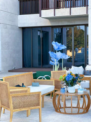 Outdoor patio area with wicker furniture, a coffee table, and decorative flowers.