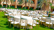 Outdoor event setup with tables, chairs, and palm trees in the background. Moments rentals