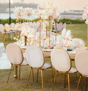 Decorative outdoor setting with tables, chairs, and floral arrangements. moments rentals