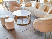 Beige textured sofa set with matching ottomans and a round coffee table in a modern interior setting.