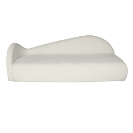 A modern, minimalist beige velvet lounge sofa with a curved, sculptural backrest, shown from a side profile view.
