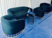 Black velvet sofa and chairs with a small table on a blue floor.