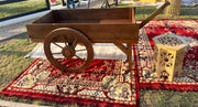 Wooden cart on a red patterned rug with a lantern in the background