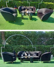 Outdoor furniture set with chairs and a table on a green lawn, surrounded by hedges.