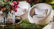 Two Beige Velvet Sofas with decorative pillows in a garden setting with flowers and candles.