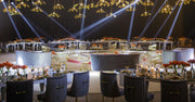 Elegant event setup with tables, chairs, and decorative elements under spotlights.