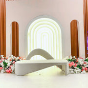 Modern Beige Velvet Bridal Sofa with a neon light arch in a decorative setting with flowers.