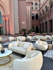 Luxurious outdoor seating area with beige sofas and coffee tables in a grand architectural setting.