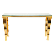 A cocktail table with a clear glass top and highly reflective, wavy gold metal legs, shown against a plain white background.