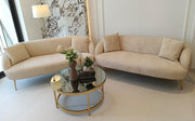 Beige sofa set with a round glass coffee table in a modern living room.