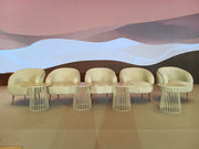 Set of beige chairs with wire legs against a colorful abstract wall.