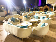 Outdoor evening setting with white chairs and blue cushions on a wooden deck.