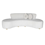 A modern curved beige velvet sofa with two matching round white throw pillows, shown against a plain white background.