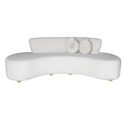 A modern curved beige velvet sofa with two matching round white throw pillows, shown against a plain white background.
