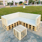 Wooden pallet outdoor furniture set with white cushions on a stone patio.