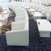 White chairs and tables arranged in a patterned room with a focus on the chairs.