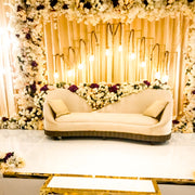 Decorative Bridal setup with a white sofa, floral arrangements, and string lights.