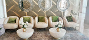 Decorative living room with patterned walls, mirrors, and green cushions on beige chairs.