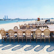 Long table with chairs on a sandy beach with a city skyline in the background