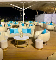 Outdoor evening setting with white furniture and blue cushions on a wooden deck.