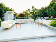 Outdoor patio area with white furniture and palm trees in the background