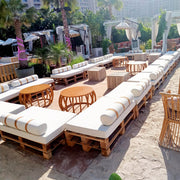 Outdoor seating area with wooden pallets and white cushions in a casual - setting - Moments Rentals