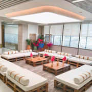 Modern indoor seating area with wooden pallet chairs and tables, decorated with plants and flowers.