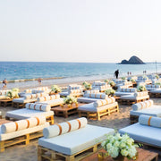 Beachside setup with pallet furniture and floral arrangements by the ocean.