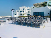 Moments Rentals Outdoor seating area with tables and chairs on a rooftop with a modern building in the background.
