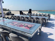 Moments Rentals Outdoor event setup with tables, chairs, and floral arrangements on a rooftop with a beach view.