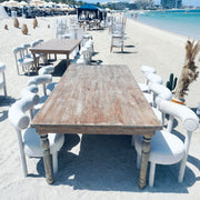 Wooden table and chairs on a sandy beach with ocean and buildings in the background in dubai