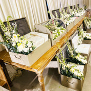 Decorative setup with floral arrangements in boxes on a wooden table.