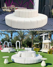 White circular sofa in an outdoor setting with palm trees and a clear sky.