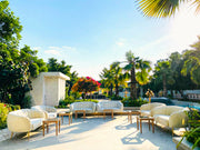 Outdoor patio area with white furniture and palm trees under a clear blue sky.