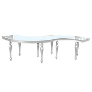 S- shaped glass table with silver metal legs on a white background