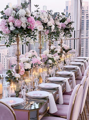 Elegant dining table setting with floral centerpieces and city skyline view.