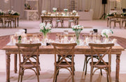 Dining setup with wooden tables and chairs in a large room.