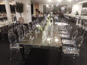 Long table set for a formal event with clear chairs and floral centerpieces.