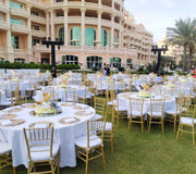 Outdoor wedding setup with tables, chairs, and decorations in front of a large building.