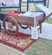 Wooden wheelbarrow with supplies on a red patterned rug outdoors