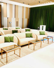 Modern living room with beige sofas, green cushions, and wooden coffee tables.