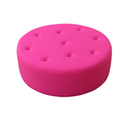 Pink round ottoman with button tufting on a white background