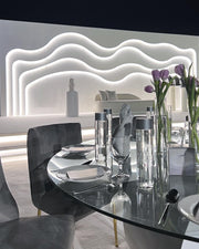 Modern dining table setting with glassware and flowers in a stylish interior.