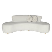 A modern curved beige velvet sofa with two round  throw pillows.